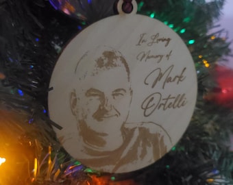 May include: A round wooden ornament with a photo of a man and the text "In Loving Memory of Mark Ortelli".