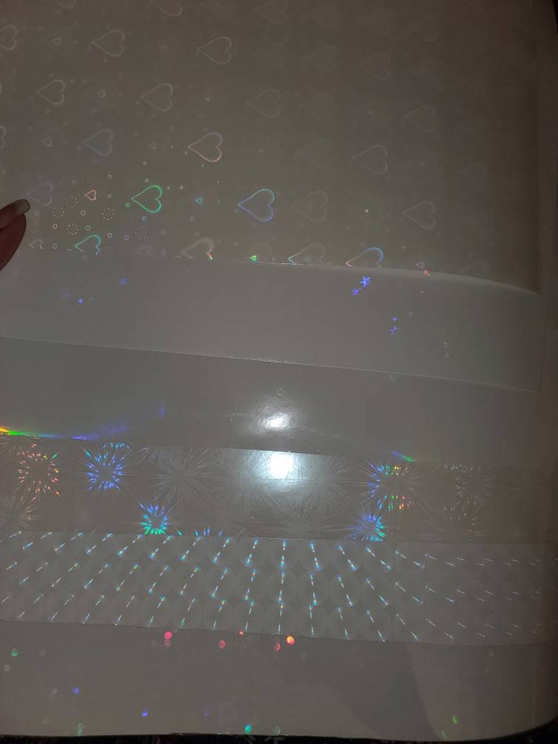 May include: A sheet of iridescent holographic paper with a variety of patterns. The patterns include hearts, fireworks, and a grid.