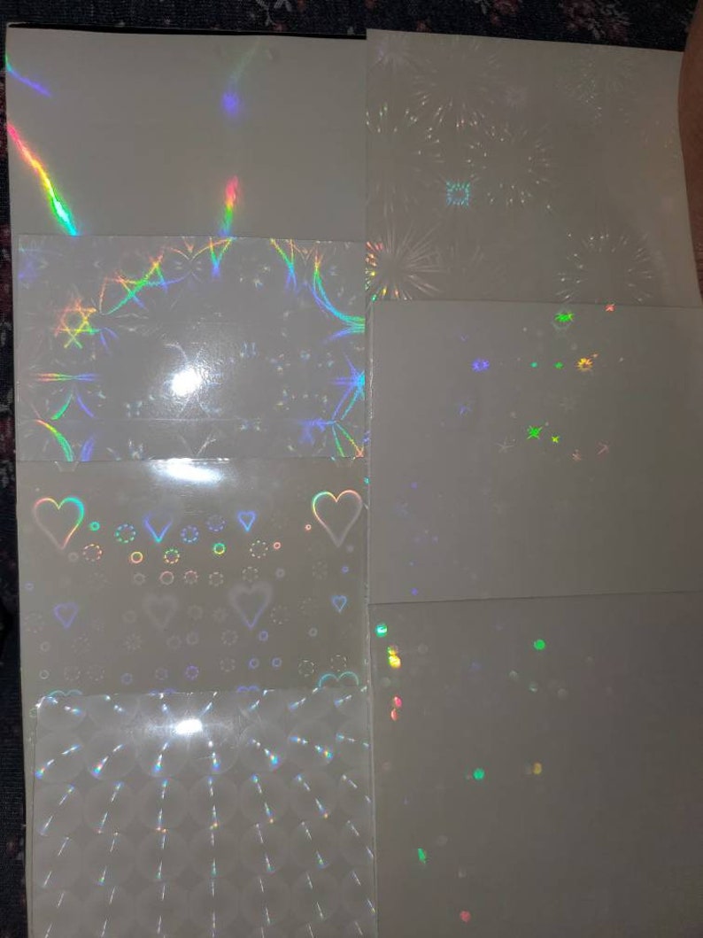 May include: A set of eight iridescent holographic sheets with different patterns. The patterns include stars, hearts, fireworks, and geometric shapes.