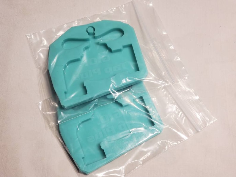 May include: Two turquoise silicone molds for making resin crafts. The molds are shaped like a dragonfly and a house.