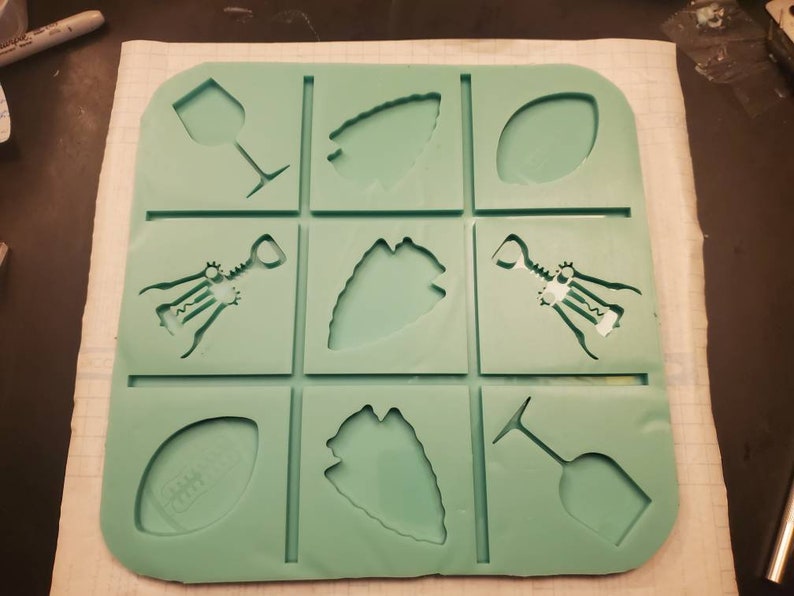 May include: Green silicone mold with nine different shapes, including wine glasses, corkscrews, and footballs.