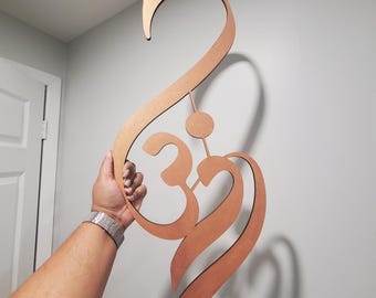 May include: A wooden wall hanging in the shape of the Om symbol, a sacred sound in Hinduism and Buddhism. The symbol is carved in a flowing, intricate design and is painted in a warm brown color.