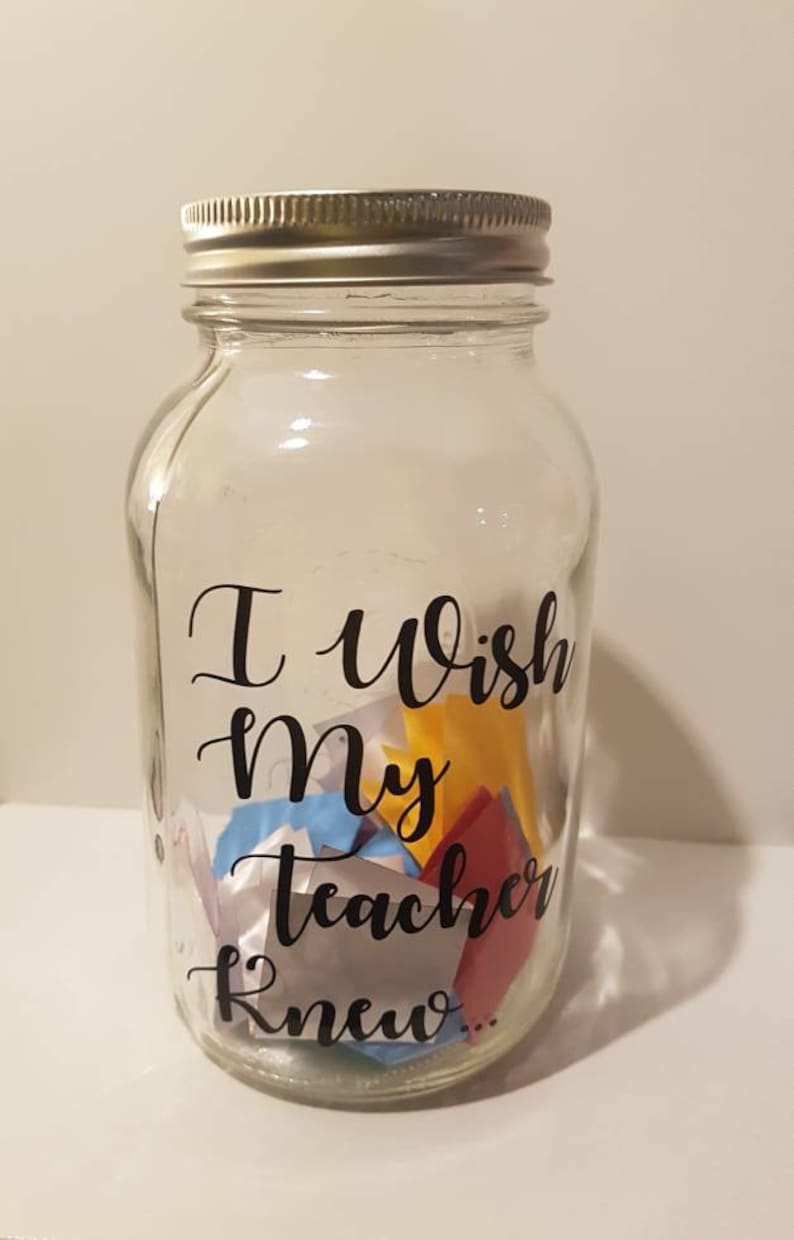 May include: A clear glass jar with a silver lid filled with colorful paper notes. The jar has a black vinyl sticker that reads "I wish my teacher knew..."