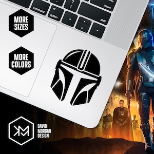 Puede incluir: Una pegatina negra con un casco mandaloriano se muestra en un port&aacute;til. La imagen incluye el texto "MORE SIZES" y "MORE COLORS" en hex&aacute;gonos negros. Tambi&eacute;n se ve el logotipo y el nombre del dise&ntilde;ador, "DAVID MORGAN DESIGN".