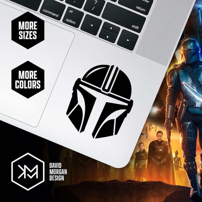 Puede incluir: Una pegatina negra con un casco mandaloriano se muestra en un port&aacute;til. La imagen incluye el texto "MORE SIZES" y "MORE COLORS" en hex&aacute;gonos negros. Tambi&eacute;n se ve el logotipo y el nombre del dise&ntilde;ador, "DAVID MORGAN DESIGN".