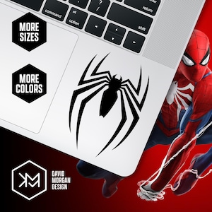 May include: A black spider logo sticker on a white laptop. The sticker is a stylized spider with long legs. The laptop is partially visible, with the keyboard and a corner of the screen. The image also includes the text "MORE SIZES" and "MORE COLORS".