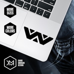 May include: A black sticker with a stylized "W" design is displayed on a white laptop. The image also includes black hexagonal graphics with the text "MORE SIZES" and "MORE COLORS". The designer's logo and name are also visible.
