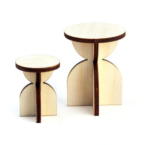 May include: Two wooden stools with a unique hourglass shape. The larger stool is about 10 inches tall and the smaller stool is about 6 inches tall.