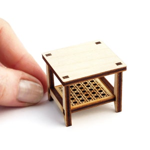 May include: A miniature wooden table with a woven shelf and a light wood top. The table is about 4 inches tall and is made of plywood.