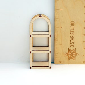 May include: A wooden three-tiered shelf unit with an arched top. The shelf is made of unfinished wood and is approximately 15 cm tall.