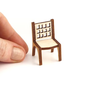 May include: A miniature wooden chair with a geometric cutout design on the back. The chair is made of light brown wood with a natural finish.