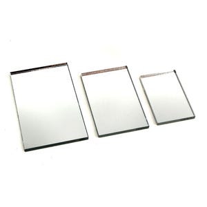 May include: Three rectangular mirrors of varying sizes. Each mirror has a reflective surface and a dark border. The mirrors are arranged in a row, with the largest on the left and the smallest on the right.