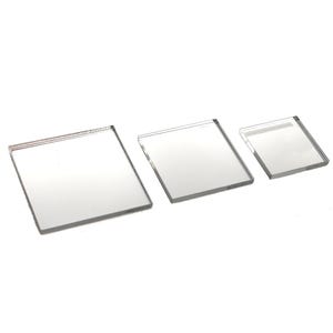 May include: Three clear, square acrylic blocks of varying sizes are arranged diagonally. The blocks are transparent, allowing light to pass through. The edges are smooth and polished, reflecting the surrounding light. The blocks are set against a white background.