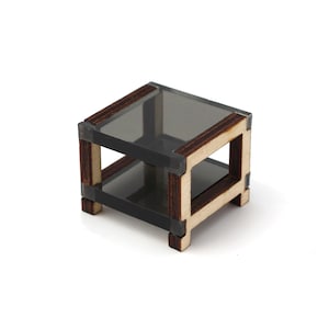 May include: A small wooden table with a glass top and a shelf. The table is made of dark wood with a light wood trim. The glass top is clear and the shelf is made of the same dark wood as the table.