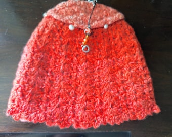 Orange crocheted handspun wool tea cozy with fabric lining.  Purl buttons decorate the top and a matching teapot charm dangles from the top.