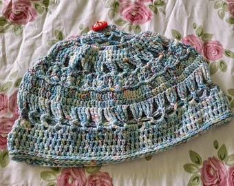 Blue colored crocheted hat with merino wool yarn.  The top is partially open with a lace look and 2 lace pannels.  A vintage button on top.