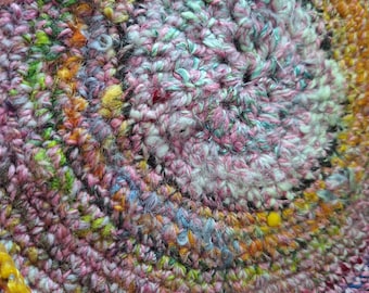 Sweet trivet crocheted with various colors of handspun wool.  I change colors and types of wool as I spin.  Golden ribbon edged.