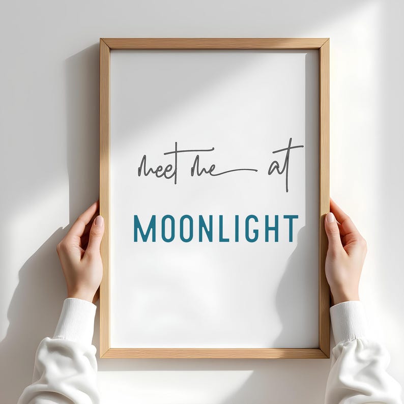May include: A framed print with the text "Meet me at MOONLIGHT" in a light blue color. The text "Meet me" is handwritten in black.