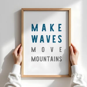 May include: A framed print with the text "MAKE WAVES MOVE MOUNTAINS" in blue and grey lettering on a white background.