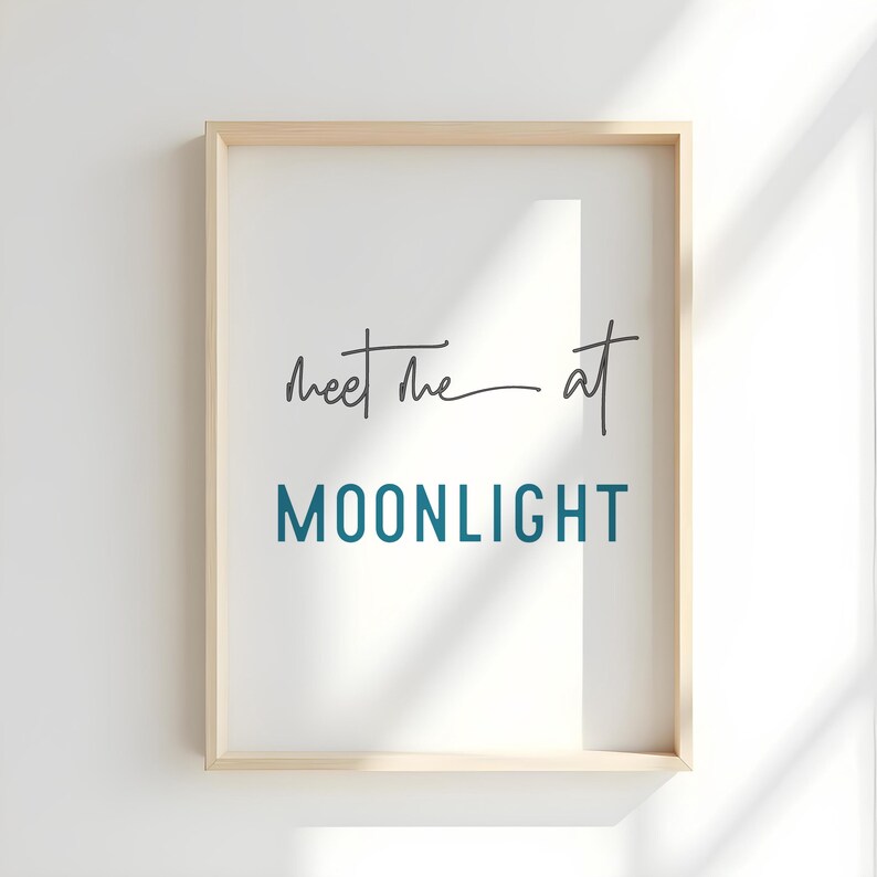 May include: A framed print with the text "Meet me at MOONLIGHT" in a teal blue color. The text is in a modern, handwritten font.