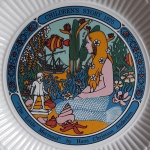 May include: A white ceramic plate with a colorful illustration of a mermaid with long blonde hair, a ship, and a small boy. The plate has the text "Children's Story 1975" and "The Little Mermaid" by Hans Christian Andersen.
