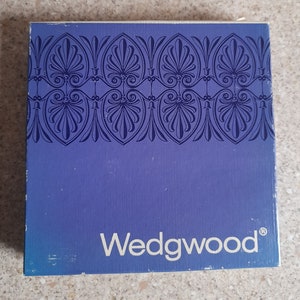 May include: A blue box with a white border and a decorative pattern on the top. The box has the word "Wedgwood" printed in white on the front.