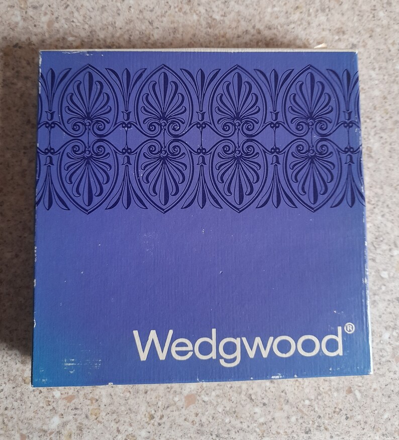 May include: A blue box with a white border and a decorative pattern on the top. The box has the word "Wedgwood" printed in white on the front.