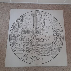 May include: A black and white line drawing of a mermaid with long flowing hair, sitting on a rock with a seashell in her hand. A small child is standing on a rock to the left of the mermaid. A ship is sailing in the background.