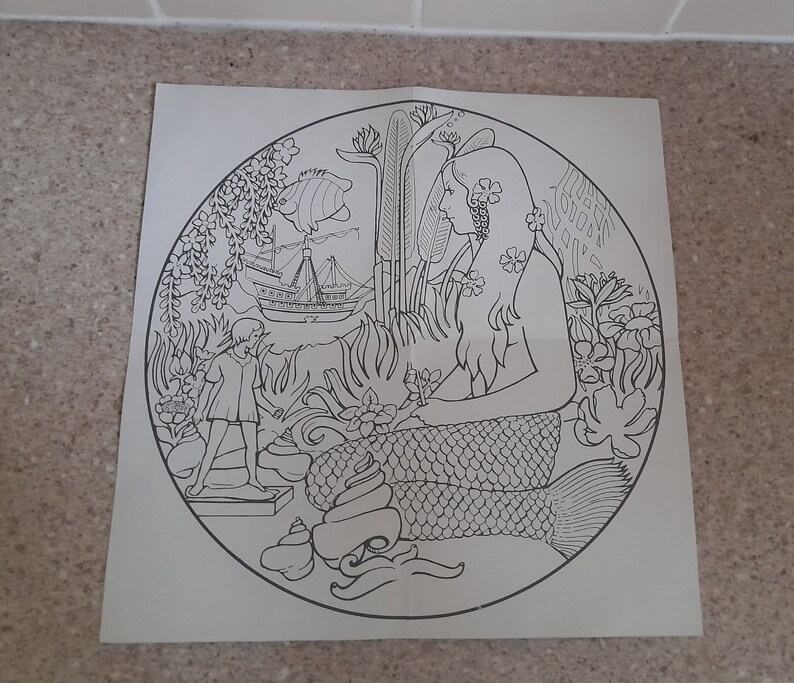 May include: A black and white line drawing of a mermaid with long flowing hair, sitting on a rock with a seashell in her hand. A small child is standing on a rock to the left of the mermaid. A ship is sailing in the background.