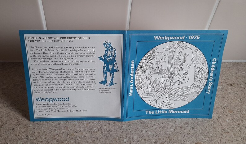 May include: A blue and white ceramic plate with a black and white illustration of a mermaid from Hans Christian Andersen's The Little Mermaid. The plate is part of a series of children's stories from Wedgwood, 1975.