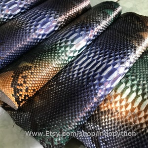 以下が含まれることがあります： 緑、青、茶色の虹色に輝くパイソン革の断片がいくつか写っています。革は、質感のある鱗模様をしています。 www.Etsy.com/shop/indobpython