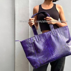 May include: A large, rectangular purple tote bag with a snakeskin pattern. The bag has two handles and a zipper closure. The bag is held by a person. The Etsy shop name "shopndopython" is visible in the image.