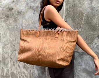 May include: A brown leather tote bag with a snakeskin pattern. The bag has two top handles and a zipper closure.
