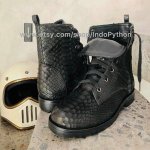 May include: Black leather boots with a snakeskin pattern and lace-up closure. The boots have a thick sole and a zipper on the side. www.etsy.com/shop/IndoPython