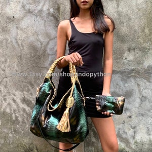 May include: A green and black snakeskin handbag with a gold tassel and a matching snakeskin clutch. The handbag has a braided strap and a black strap.