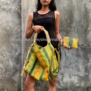 以下が含まれることがあります： 緑と黄色のヘビ革のハンドバッグと、それに合わせたヘビ革のクラッチバッグ。ハンドバッグには、編みこまれたロープのハンドルとタッセルが付いています。