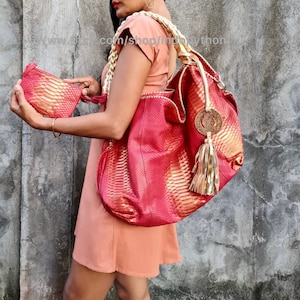 May include: A red and gold snakeskin handbag with a gold tassel and a matching smaller clutch. The bag has a woven gold strap.