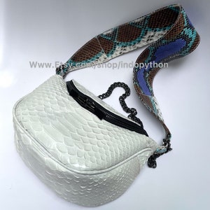 May include: White snakeskin handbag with a brown, blue, and white snakeskin strap and a black chain strap. The bag has a zipper closure and a small pocket on the front. The strap has the text "www.etsy.com/shop/indopython" on it.