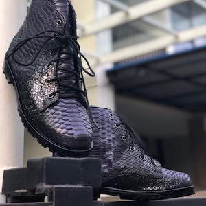 May include: A pair of black leather boots with a snakeskin pattern. The boots have laces and a chunky heel.