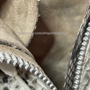 May include: Close-up of a zipper on a white snakeskin handbag. The zipper is silver and the snakeskin is textured. The text "www.Etsy.com/shop/indopython" is visible in the image.