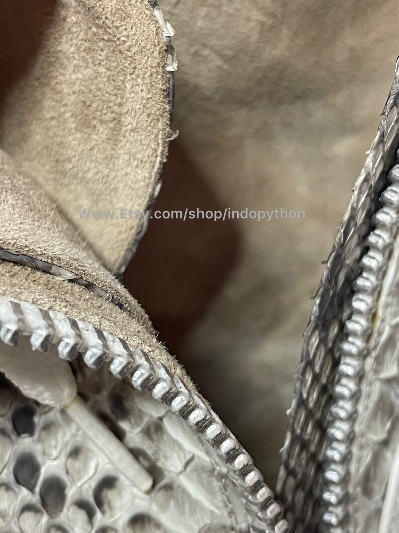 May include: Close-up of a zipper on a white snakeskin handbag. The zipper is silver and the snakeskin is textured. The text "www.Etsy.com/shop/indopython" is visible in the image.