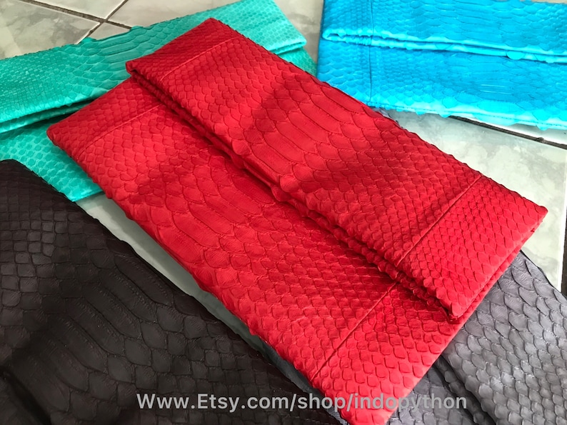 Peut inclure: Plusieurs pochettes color&eacute;es et textur&eacute;es, rouges, turquoise, et noires. Les sacs pr&eacute;sentent un motif en &eacute;cailles, sugg&eacute;rant une peau de reptile. L'URL de la boutique Etsy est visible en bas de l'image.