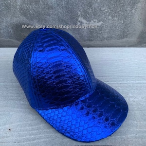 May include: A blue baseball cap with a crocodile-embossed leather design. The cap has a curved brim and a structured crown.