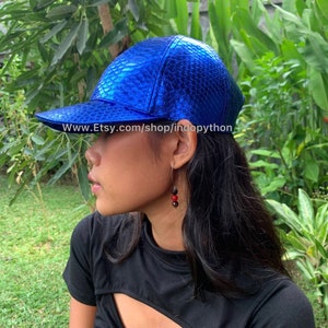 May include: A blue snakeskin baseball cap with a curved brim. The cap has a shiny, metallic finish. The text "www.Etsy.com/shop/indopython" is printed on the brim.