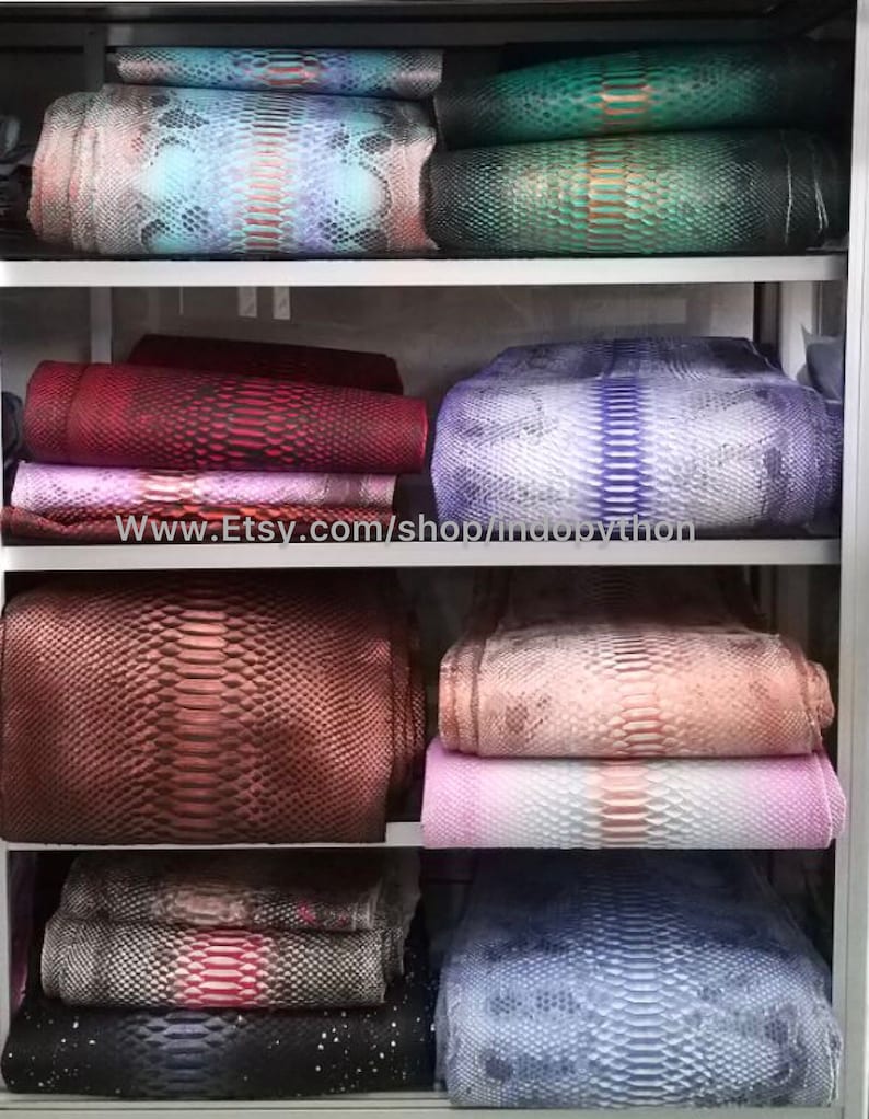 Może przedstawiać: P&oacute;łka z r&oacute;żnymi kolorami i wzorami sk&oacute;ry pytona. Sk&oacute;ra jest ułożona w stosy na p&oacute;łkach. Tekst "www.Etsy.com/shop/indopython" jest widoczny na p&oacute;łce.