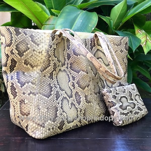 Könnte beinhalten: Eine große, hellbraune Python-Ledertasche mit einer passenden kleineren Clutch. Die Tasche hat ein Schlangenhautmuster und ist aus echtem Leder gefertigt.