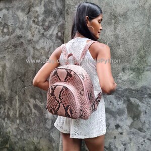K&ouml;nnte beinhalten: Ein rosafarbener Python-Lederrucksack mit einem schwarz-wei&szlig;en Muster. Der Rucksack hat einen Rei&szlig;verschluss und verstellbare Tr&auml;ger. www.etsy.com/shop/IndoPython