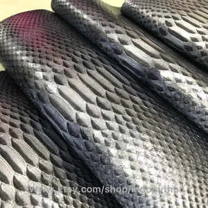 Może przedstawiać: Zbliżenie na kawałek czarnej i srebrnej skóry węża. Skóra ma fakturowany, łuskowaty wzór.