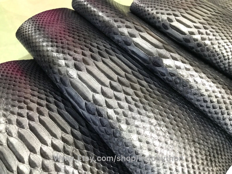 May include: Close-up of a piece of black and silver snakeskin leather. The leather has a textured, scaly pattern.