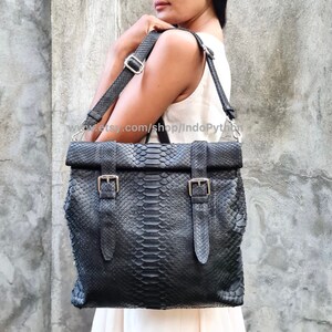 Peut inclure: Sac fourre-tout en cuir noir avec un motif en peau de serpent et des boucles argent&eacute;es. Le sac a une longue bandouli&egrave;re r&eacute;glable et un rabat.